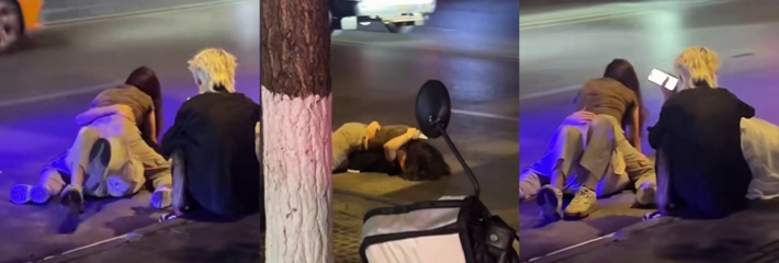 夜晚街头醉酒情侣路边趴地拥抱 金发朋友坐旁玩手机无奈等候